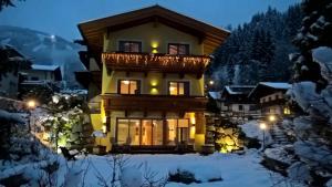 a house with a balcony in the snow at night at Landhaus Marlies in Zell am See