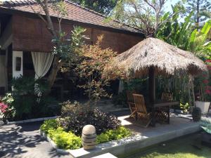 eine Terrasse mit einem Tisch und einem Strohschirm in der Unterkunft Nike Villas in Sanur