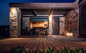 a patio with a stone wall and a wooden deck at Keros Blue - Luxury in Wilderness in Kalliópi