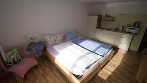 ein kleines Schlafzimmer mit einem Bett und einem Stuhl in der Unterkunft Rauhbergerhof in Tiefgraben