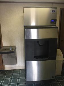 a stainless steel refrigerator in a kitchen with a sink at Super 9 Motel Troy in Troy