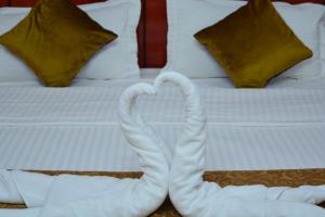Dos cisnes haciendo un corazón en una cama en Al Karam Hotel Apartment en Nizwa