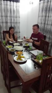 un uomo e una donna seduti a un tavolo con del cibo di Ahasna Family Villa a Negombo