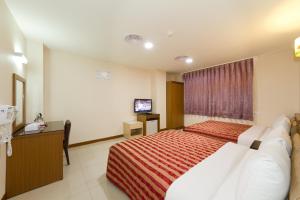 um quarto de hotel com uma cama e uma televisão em Songshan Hotel em Kaohsiung