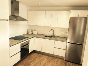 a kitchen with white cabinets and a stainless steel refrigerator at Apartments Las Floritas in Playa de las Americas