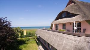 a thatch roofed building with a view of the ocean at Romantik Hotel Namenlos in Ahrenshoop