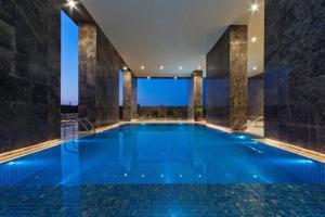 voco Doha West Bay Suites, an IHG Hotel في الدوحة: مسبح كبير مع ماء ازرق في مبنى