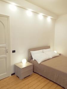 a white bedroom with a bed and a night stand at Luxurious Street Apartments in Catania