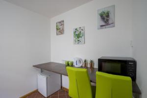 a kitchen with a table with a microwave and green chairs at Studio Ztracená 8 in Olomouc