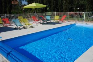 un grupo de sillas y una sombrilla junto a una piscina en Camping les Tournesols, en Sillé-le-Guillaume