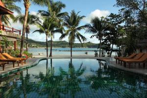 a swimming pool next to a beach with palm trees at Longtail Beach Resort in Thong Nai Pan Yai