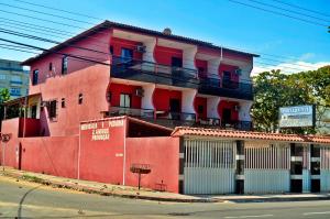 um edifício vermelho com uma varanda em cima em Pousada da Zezé em Guarapari