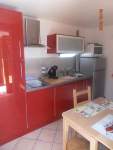 une petite cuisine avec des placards rouges et une table dans l'établissement Le chalet, à Briançon