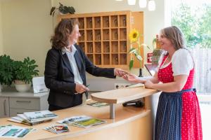 two women shaking hands at a counter in a store at Tscheppe Lang-Gasthof in Leutschach