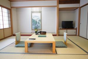 Pokój ze stołem, krzesłami i telewizorem w obiekcie Suizansou w mieście Toyooka
