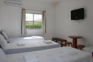 a room with two beds and a flat screen tv at Pousada Sol Nascente in Piranhas +64 photos