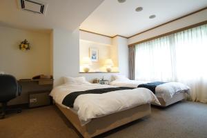 sypialnia z 2 łóżkami i oknem w obiekcie Suizansou w mieście Toyooka