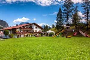 une maison avec une aire de jeux dans un champ verdoyant dans l'établissement Ferienhaus Kirchplatzl, à Leutasch