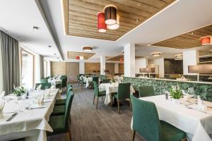 una sala da pranzo con tavoli bianchi e sedie verdi di Hotel Miramonti a Badia
