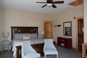 a bedroom with a bed with two chairs and a ceiling fan at The Retreat At Norwich Lake in Huntington