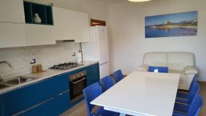 cocina con mesa blanca y armarios azules en CasaAle, en Alghero