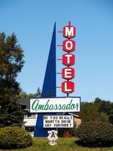 un panneau devant un bâtiment avec un panneau de motel dans l'établissement Ambassador Motel, à Sault-Sainte-Marie