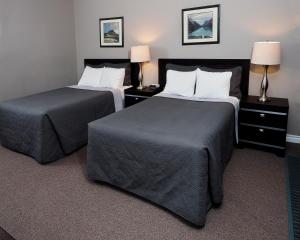 a hotel room with two beds and two lamps at Ambassador Motel in Sault Ste. Marie