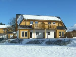 a house in the snow with a fence at Ferienpark An der Seebrücke in Ostseebad Koserow