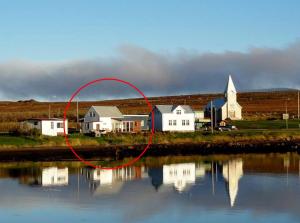 a red circle in front of a house next to the water at Guesthouse Lyngholt in Þórshöfn