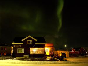 una casa con la aurora en el cielo por la noche en Guesthouse Lyngholt, en Þórshöfn