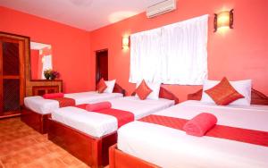 a room with four beds with red walls at Blossoming Romduol Boutique in Siem Reap