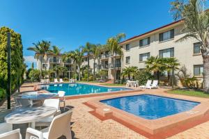 una piscina con mesa y sillas junto a un edificio en Great Eastern Motor Lodge en Perth