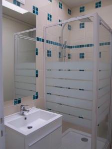 een witte badkamer met een wastafel en een douche bij Résidence les Peupliers in Chamalières