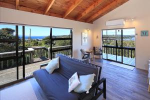 a living room with a couch and a balcony at Church Bay Views in Oneroa
