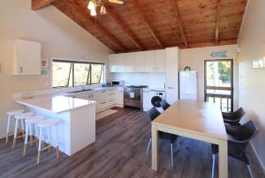 a kitchen with a table and some chairs in it at Church Bay Views in Oneroa