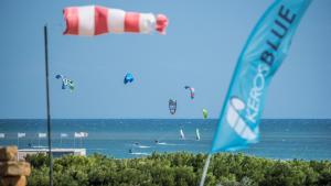 a beach with flags and people in the water at Keros Blue - Luxury in Wilderness in Kalliópi