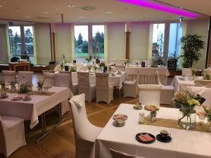 un comedor con mesas blancas y sillas blancas en Hotel Seehof Leipzig en Zwenkau