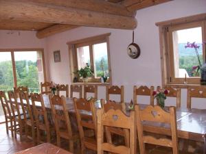 a dining room with a table and chairs and windows at Chambres d'hôtes la Ferme du Canard Argenté in Provenchères-sur-Fave