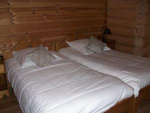 two beds in a wooden room with white sheets and pillows at Chambres d'hôtes la Ferme du Canard Argenté in Provenchères-sur-Fave