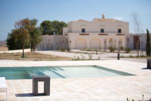 een zwembad met een gebouw op de achtergrond bij Masseria Fontana di Vite in Matera