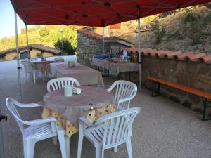 un tavolo e sedie sotto un ombrellone rosso di La Valle dei Fiori di Bellucci Rosanna a Torre deʼ Calzolari
