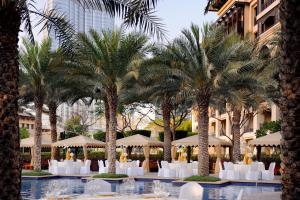 a resort with palm trees and white chairs and umbrellas at Palace Downtown in Dubai