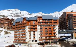 a building with snow covered mountains in the background at Chez Carole et Arnaud in Val Thorens