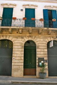 budynek z zielonymi drzwiami i niebieskimi oknami w obiekcie A Casa di Antonella w mieście Vittoria