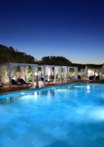 a large swimming pool with chairs and umbrellas at RELAIS MASSERIA CASINA DEI CARI in Presicce