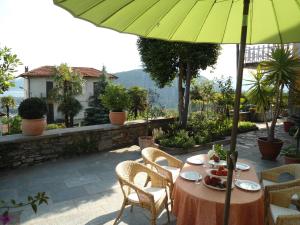 una mesa con una sombrilla verde en el patio en Casa Bureglio en Verbania