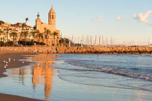 a view of a beach with a church and the ocean at Sitges Studio in Sitges