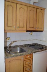 a kitchen with a sink and wooden cabinets at Plazamar in Torremolinos