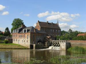 a large brick building next to a body of water at Aubépine in Sains-du-Nord