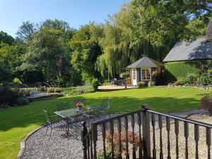 a patio with a table and chairs in a garden at Weir Cottage in Fordingbridge
